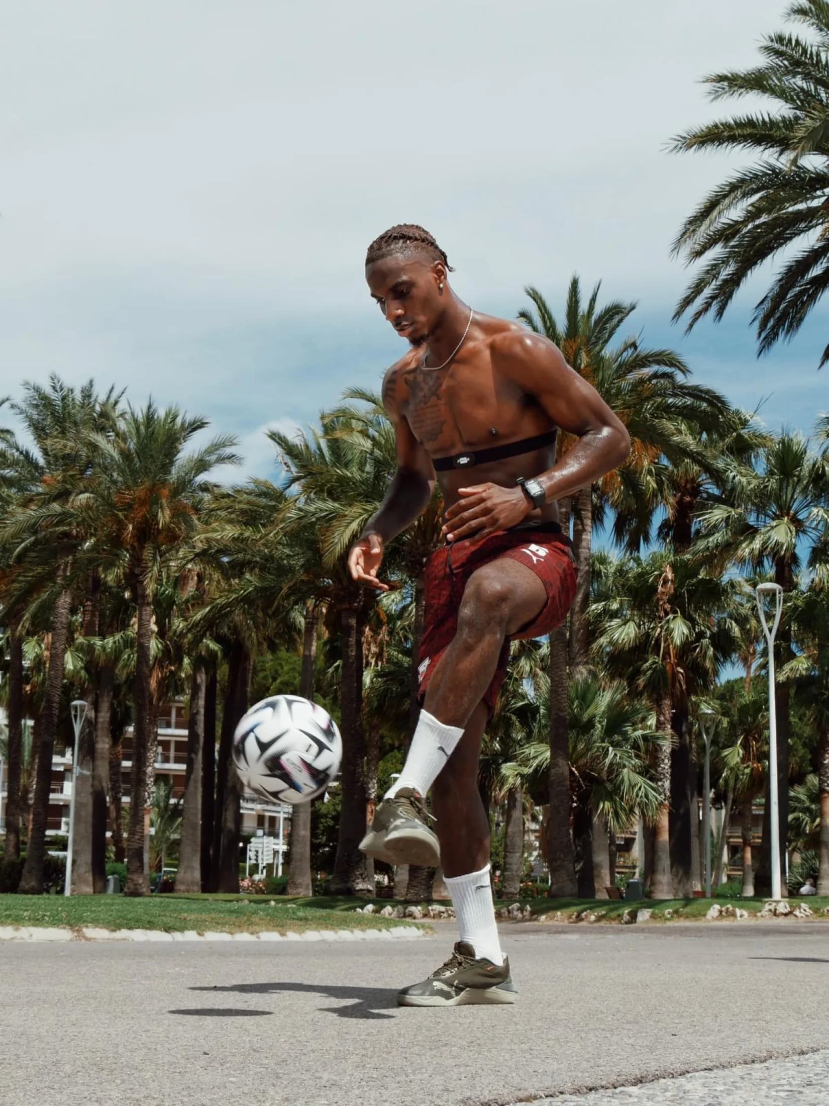 Player juggling on a palm-lined road
